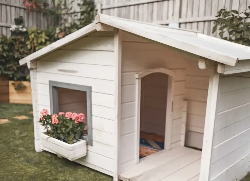 15 Clever Ways to Upgrade Your Dog Kennel With Verandah 15 White cottage-style dog kennel with pink flowers in window box and covered porch