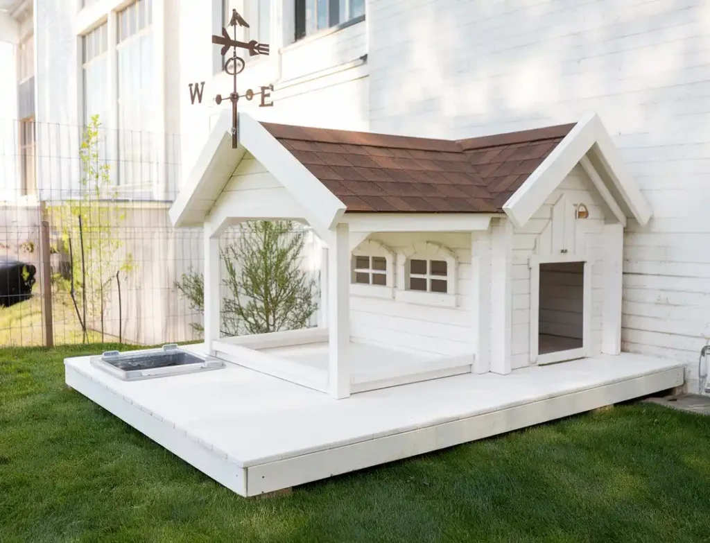 15 Clever Ways to Upgrade Your Dog Kennel With Verandah 3 White dog house with brown roof, weather vane, and attached covered run area